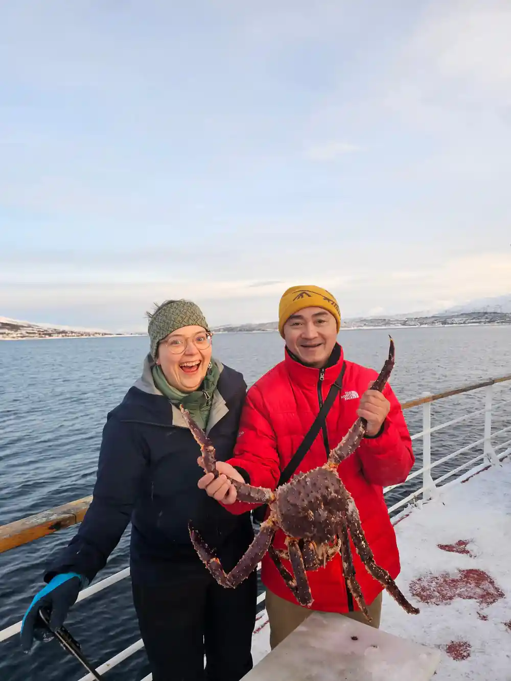 A couple on deck holding a king crab between them