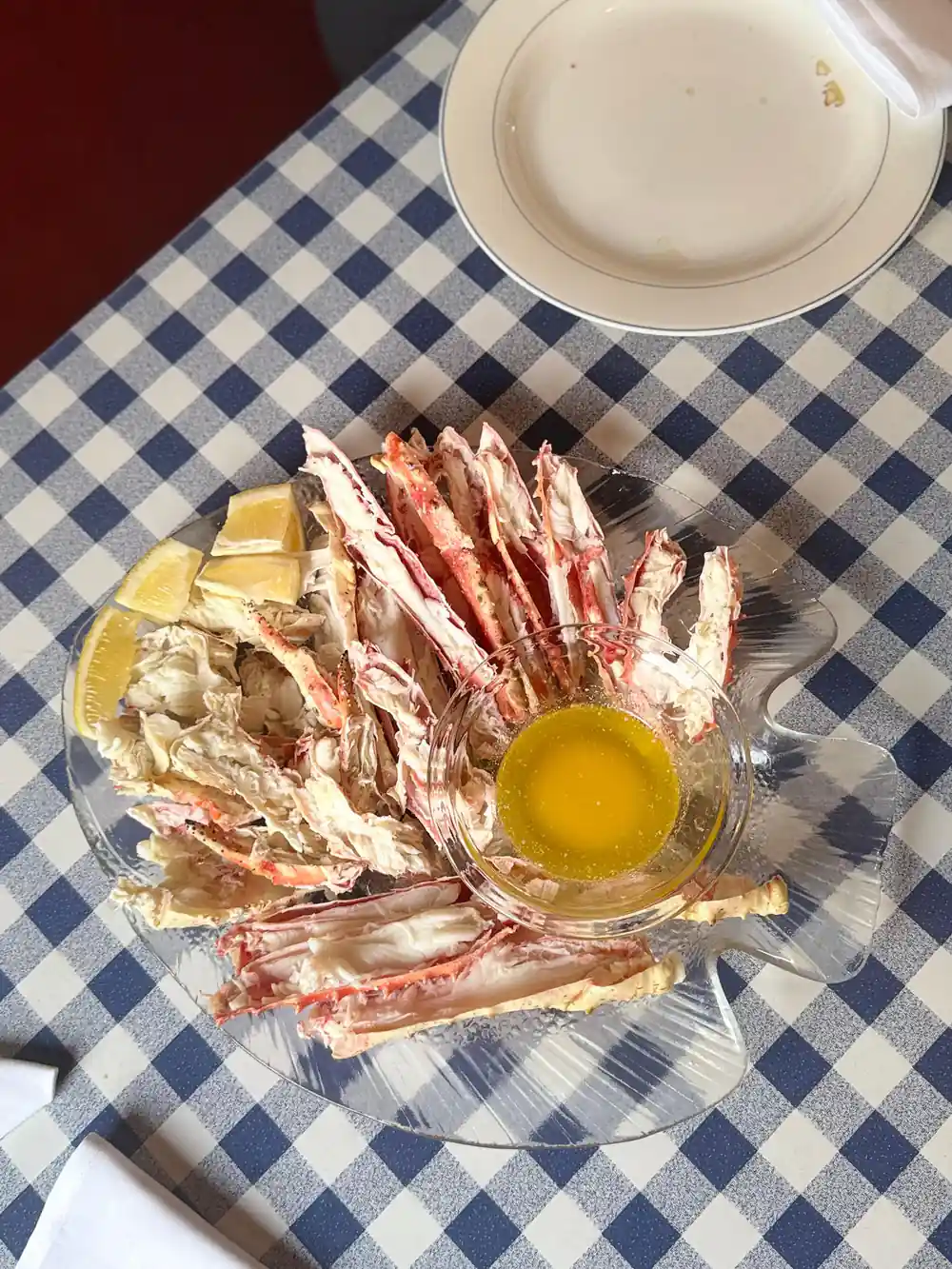 Crab legs and butter on a blue checked tablecloth