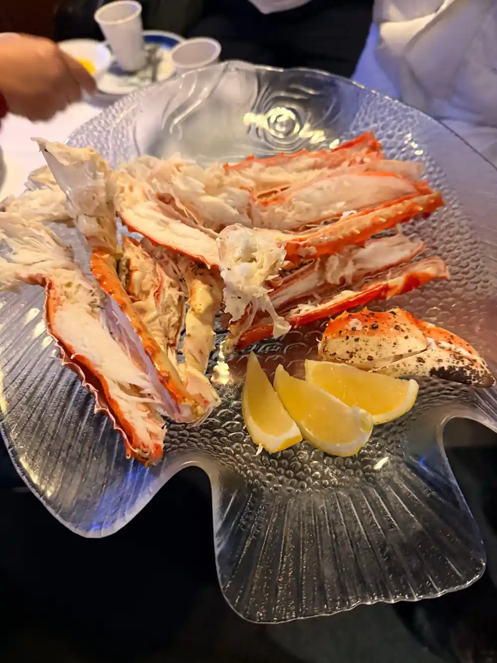 Crab legs and lemon on a glass platter being served