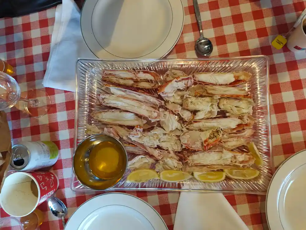 Foil tray of prepared crab legs with butter on a checked cloth