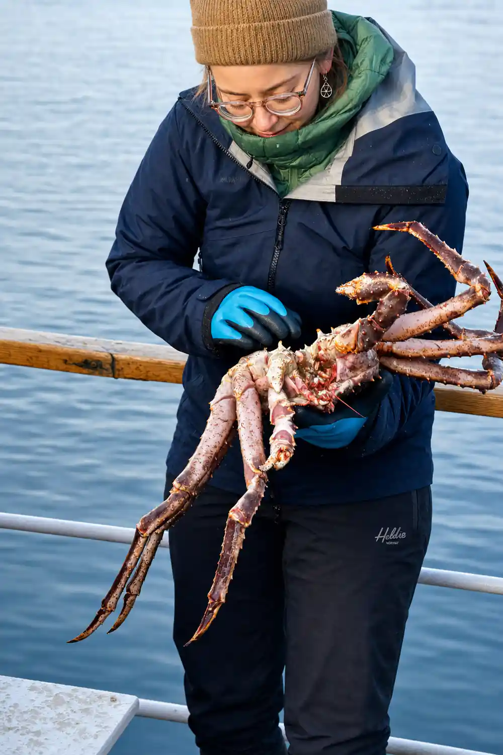 A guest carrying a large king crab along the rail