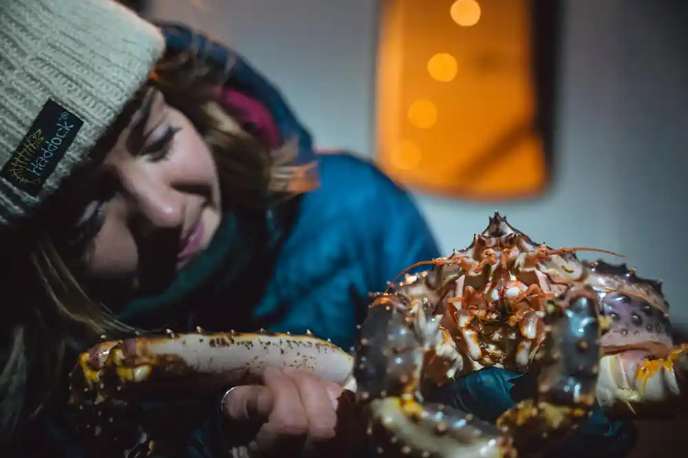 Guest laughing while holding a cooked king crab at the table