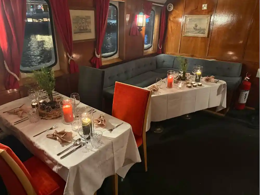 Laid dining tables with white cloths and candles in the wood-panelled saloon