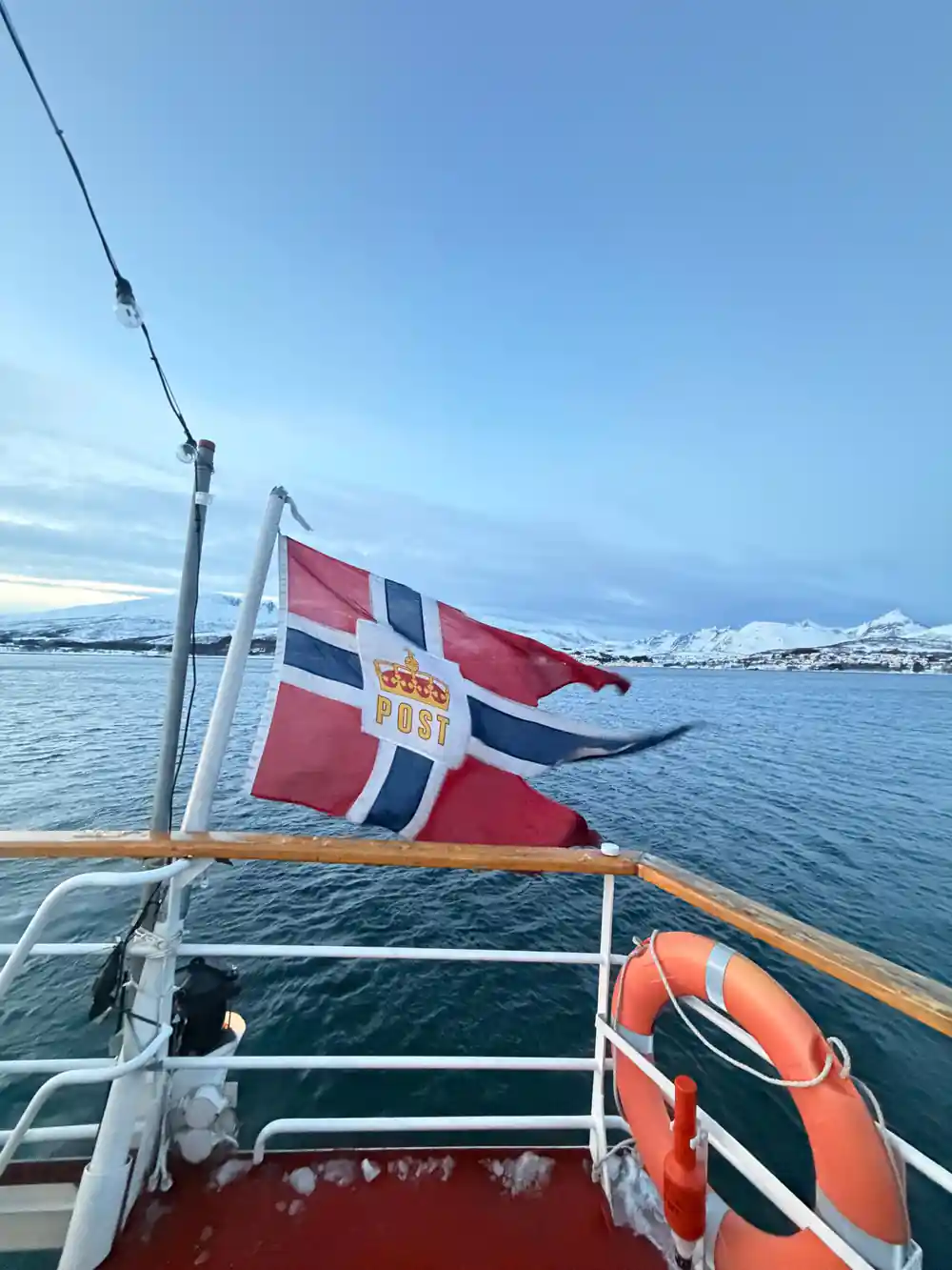 The Norwegian flag flying at the stern above the water