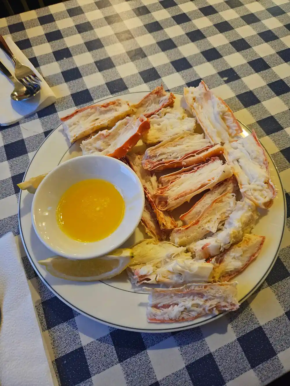 Plate of crab legs and melted butter on a checked cloth
